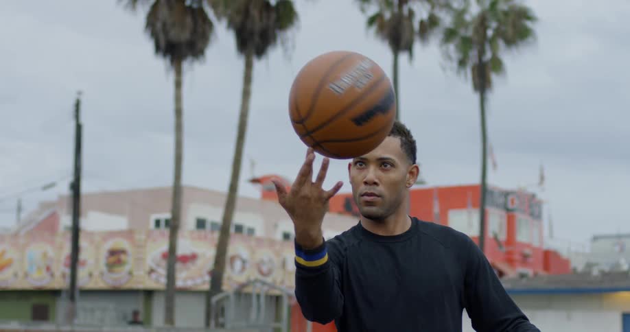 A man spins a basketball on his fingertip