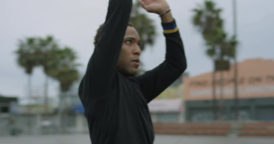 Man tosses a basketball as he stands outdoors