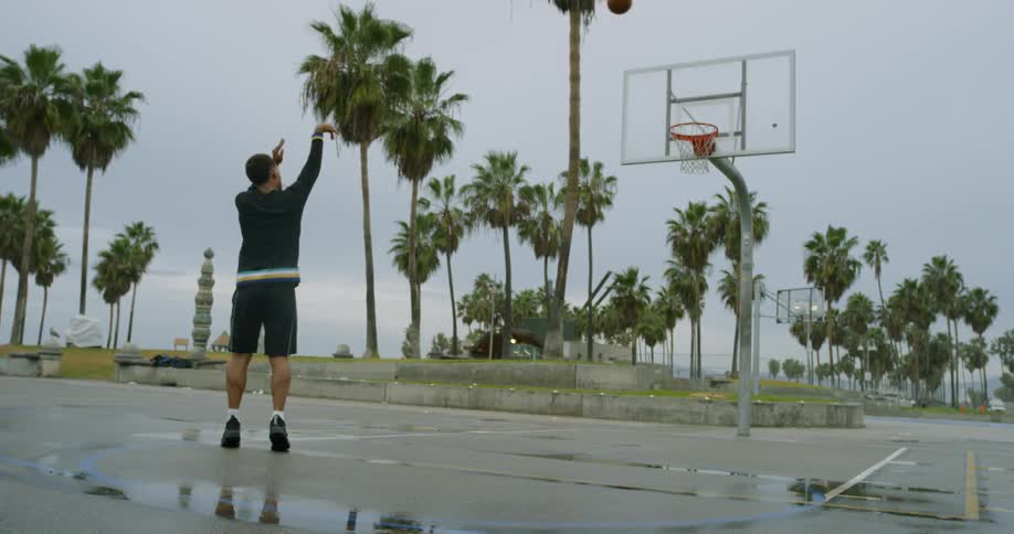 A black man plays basketball on an outdoor court