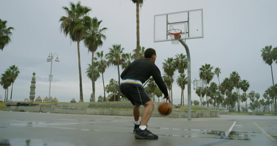 Man dribbles basketball then turns and misses shot