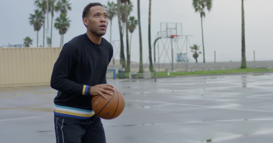 Man dribbles basketball the jumps to take shot
