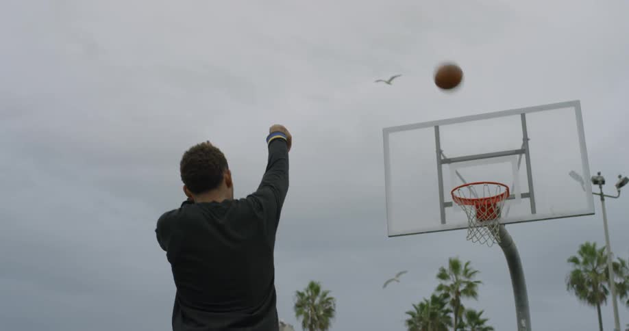 A man shoots a ball into a hoop