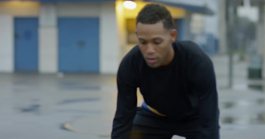Man dribbles basketball on wet asphalt