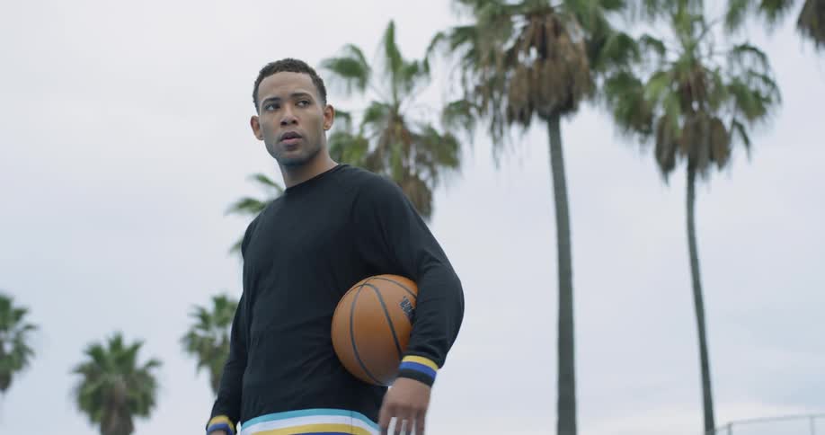 A man is tossing a basketball around in the park