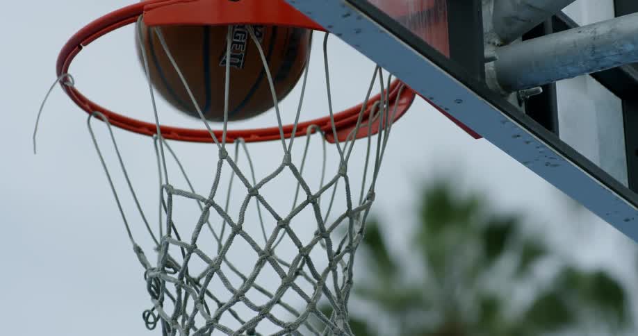 A basketball falls through a basketball net