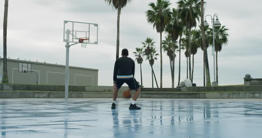 Man dribbling basketball on wet court