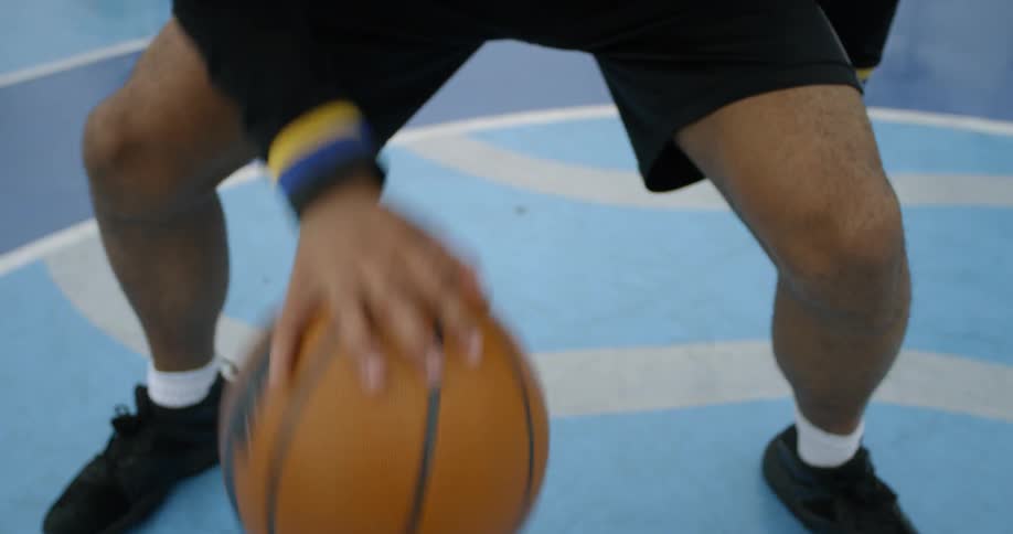 A black man dribbles a basketball between his legs