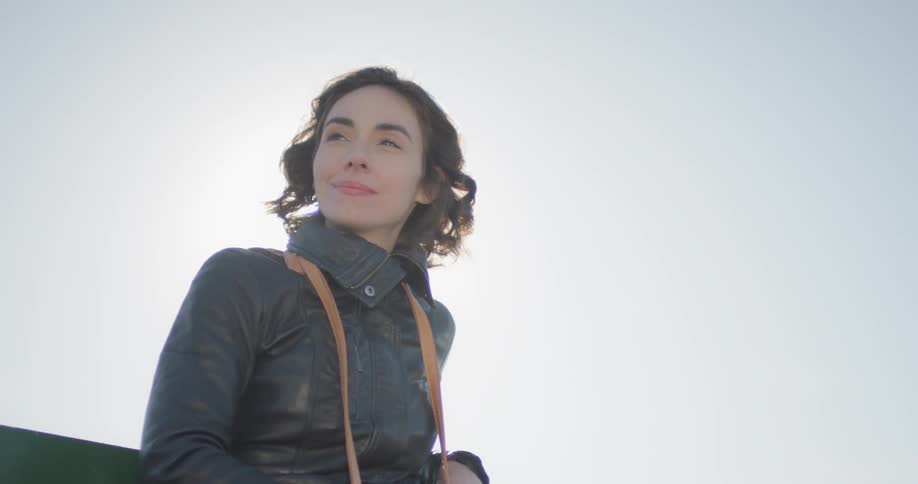Woman stands looking around under bright sun