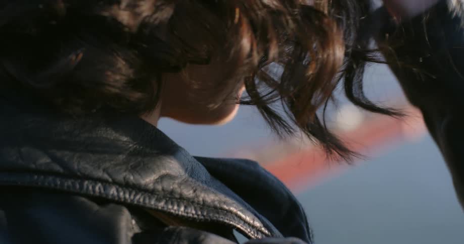 A woman stands and looks down at the golden gate bridge