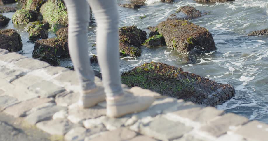 Someone walks to the edge of a brick walkway and looks out over the ocean