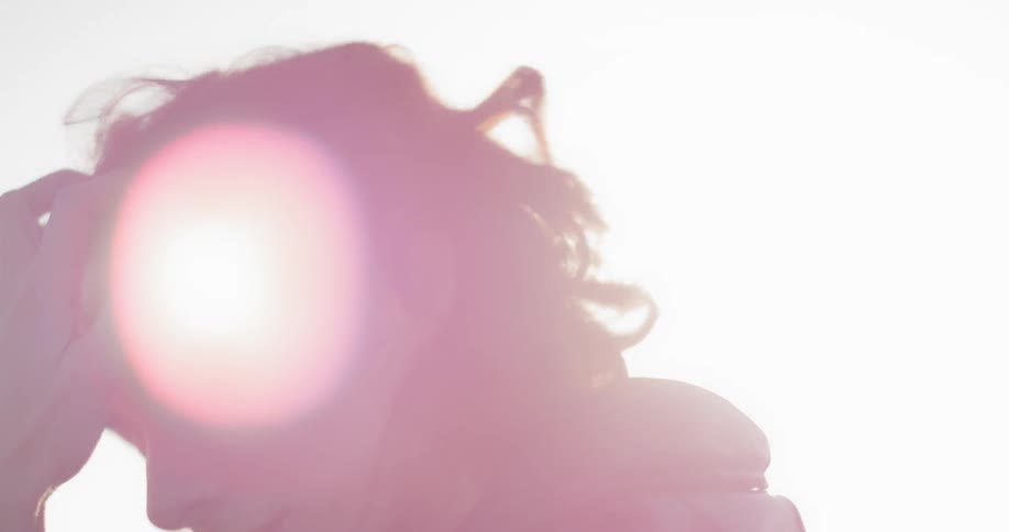 A female with dark hair takes off a pair of white headphones and runs her fingers through her hair