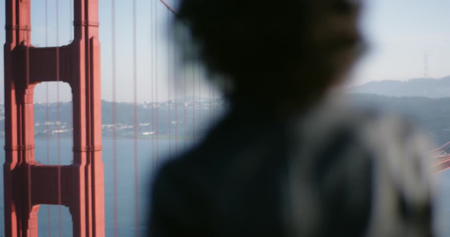 A woman stands outdoors and looks at the golden gate bridge