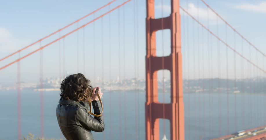 A woman takes a picture of the golden gate bridge
