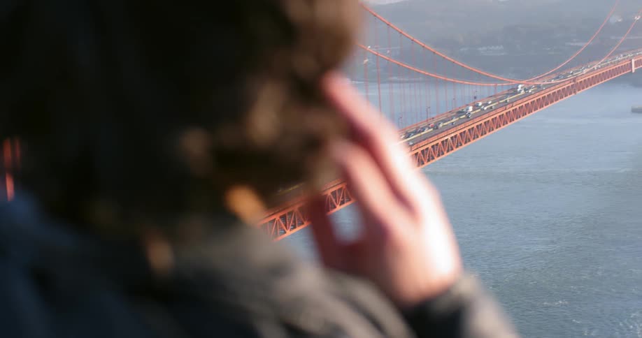 A person is looking out over the cars traveling on the bridge
