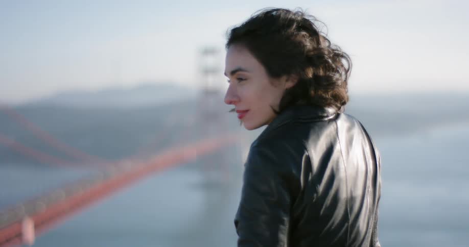 A woman is smiling looking at a bridge