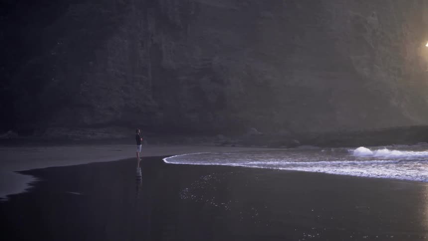 Person Standing Alone on a Quiet Beach With Calm Ocean Waves.