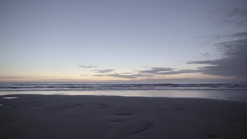 Sunset Over Beach Shoreline with Gentle Waves at Golden Hour Light Outdoors.