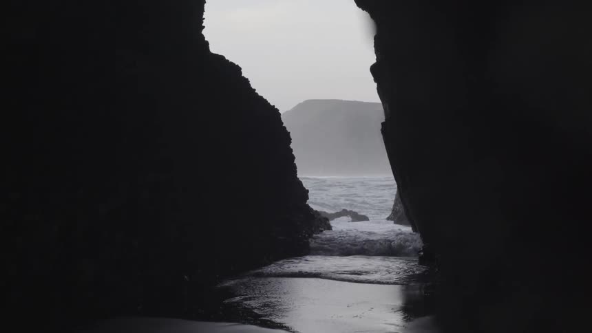 Coastal Sea Cave on Rocky Shoreline with Ocean Waves Under Natural Daylight.