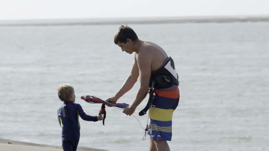A man and young boy walk on a sandy beach