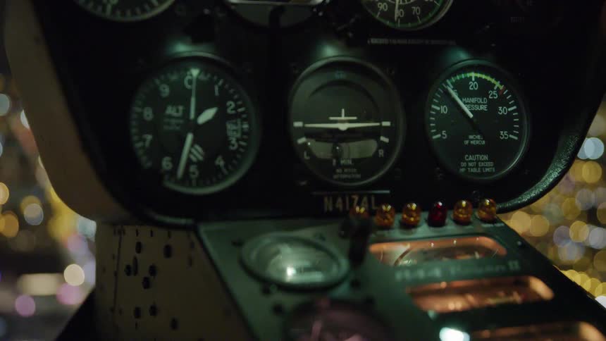 Instrument panel inside of an airplane as it flies across a city at night