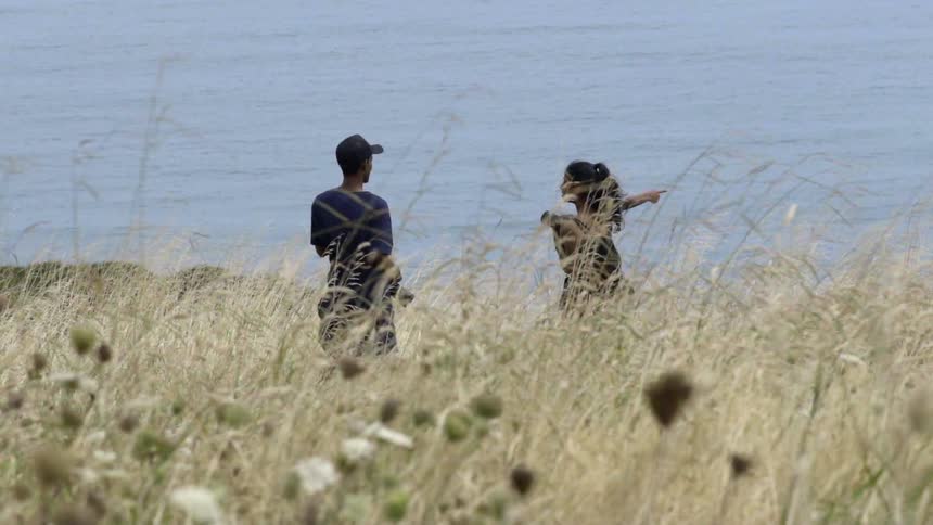A man and woman stand by the water on a cloudy day