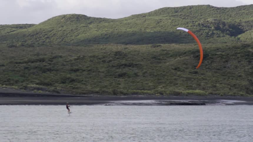 People are parasailing in a body of water on a cloudy day