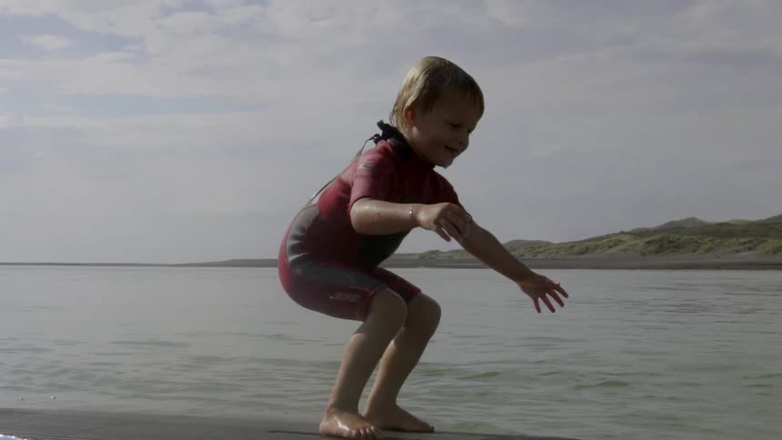 Small Boy Finding His Balance While Standing on a Surfboard in Gentle Sea.