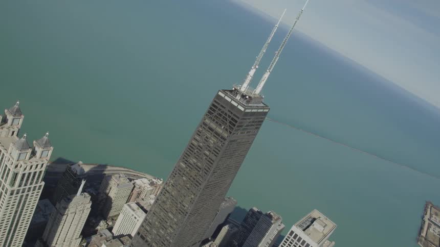 A tall skyscraper sits near the shore near other buildings