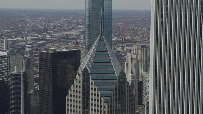 A skyscraper with a point on top surrounded by other buildings in a large city