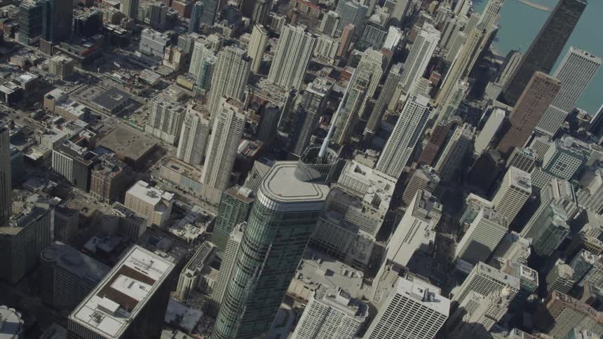 A large city with many skyscrapers high rises and a tower with a large pole