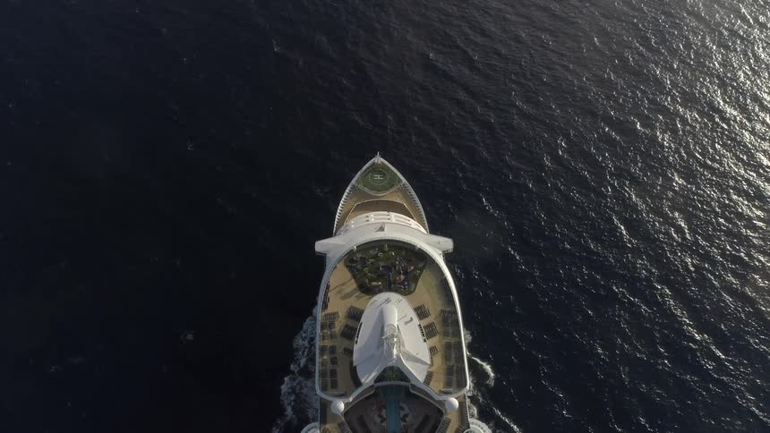 An enormous yacht with many amenities steadily sails atop a calm ocean