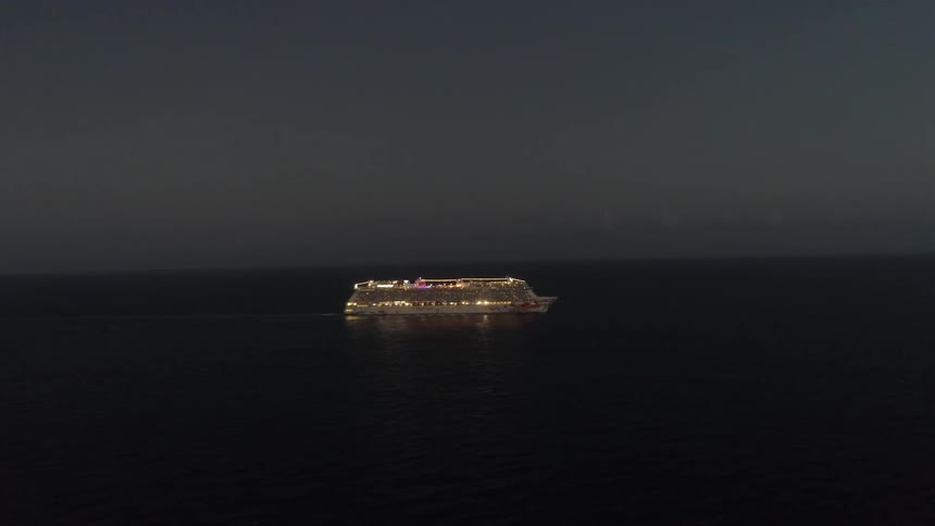 A ship covered with lights is traveling over the water