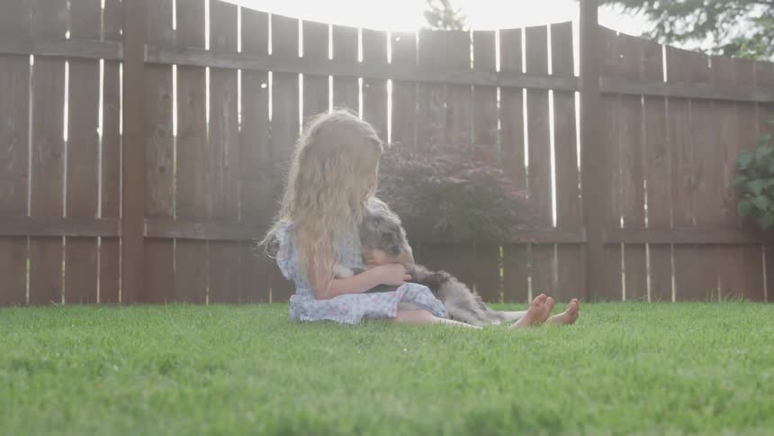 Girl holding a puppy in the yard
