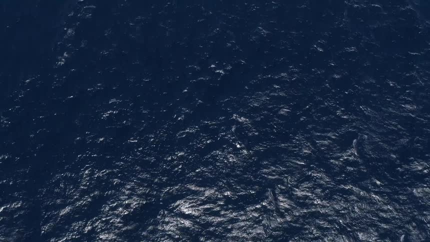 Dark blue ocean water with sunlight reflecting off the surface
