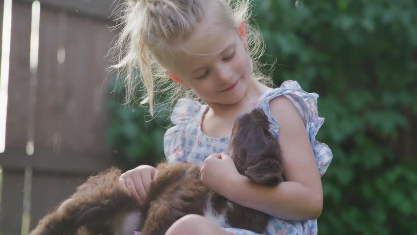 Girl in a dress playing with puppy in backyard