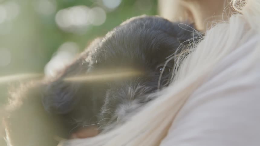 A woman sitting outdoors holding a black puppy