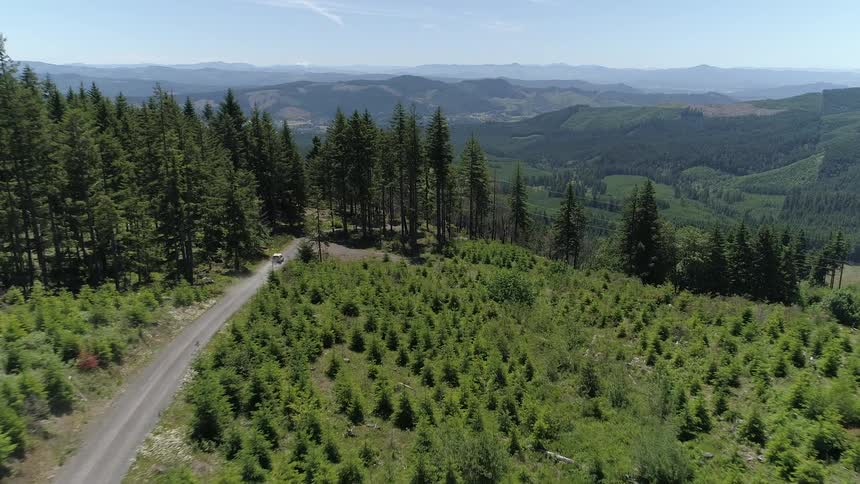 Camera flies over the mountain road with a moving car on it