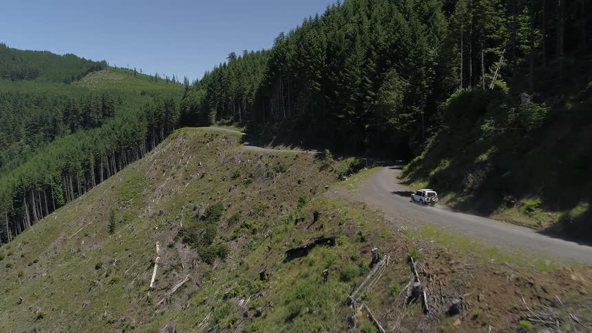 A car drives on a road traversing a hillside