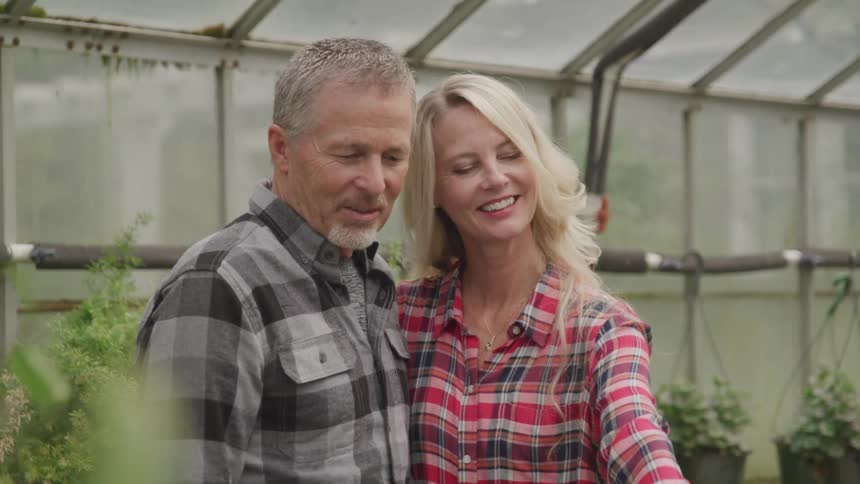 Two people look at plants in a greenhouse
