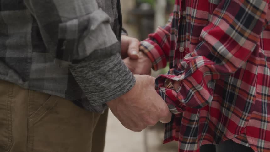 A man and woman in plaid shirts hold hands