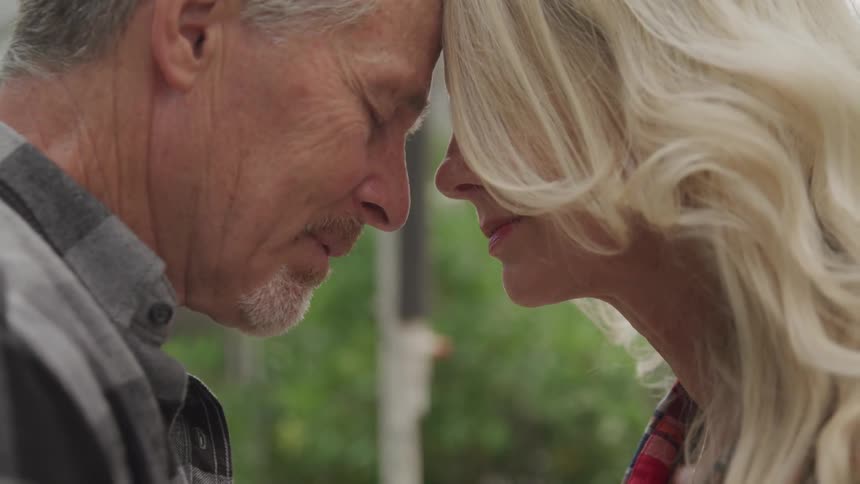 A man and woman rest their heads together with their eyes closed