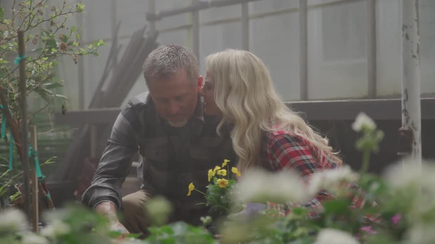 A woman leans in and kisses a man on the cheek