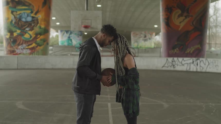 Two people stand with a basketball in the middle of them