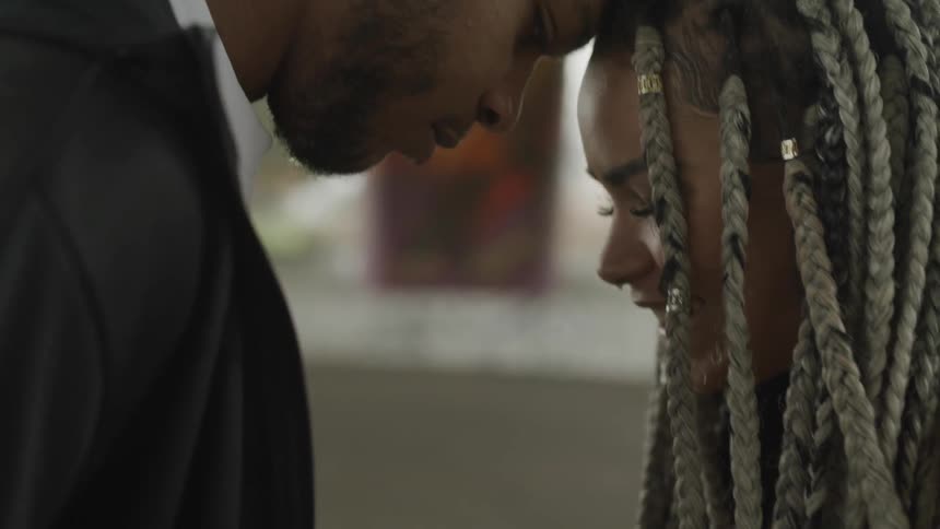 A man and woman smile while leaning their heads together