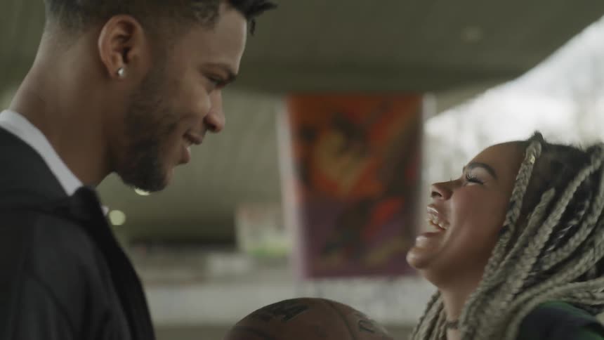 A teenage boy and girl flirt and laugh while holding a basketball