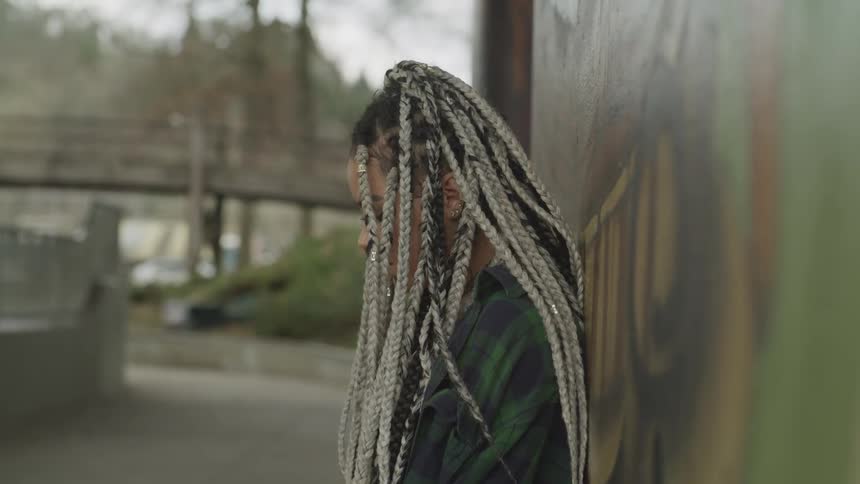 A woman leans against a wall