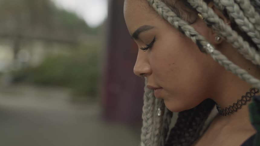 A young girl stands with her eyes closed