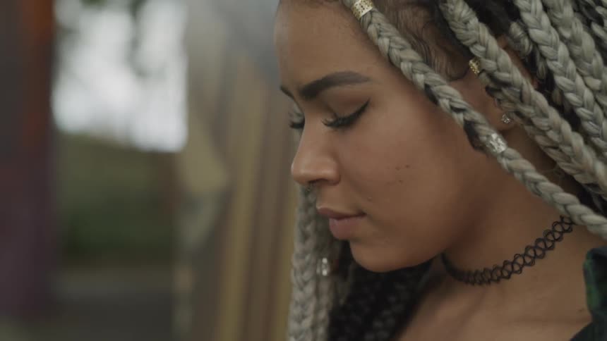 A woman with long braids smiles and looks down