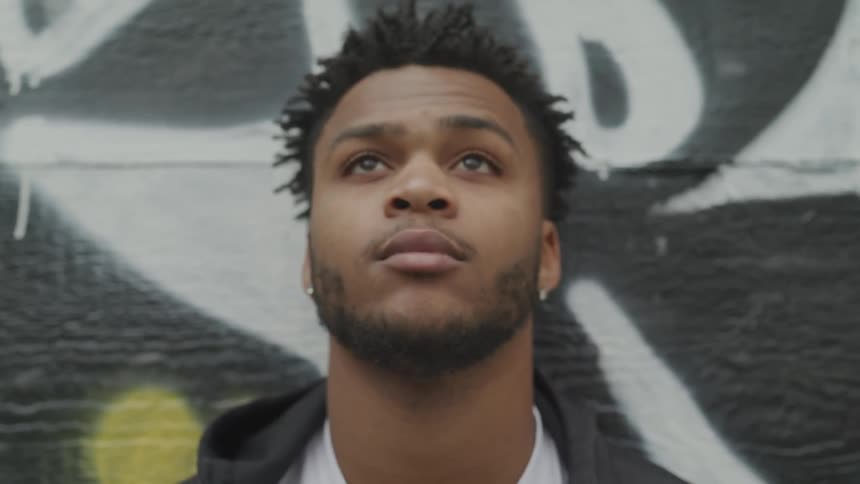 A black man staring into the sky with a deep thought