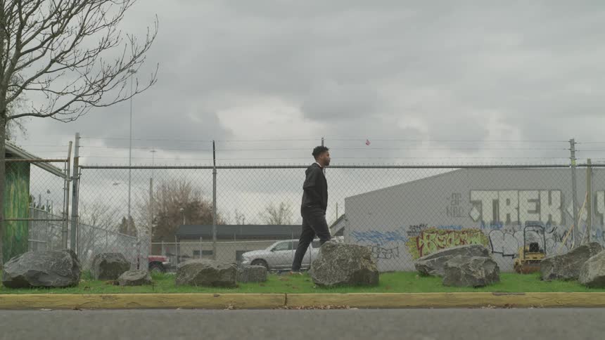 A man walks down the sidewalk with his hands in his pockets